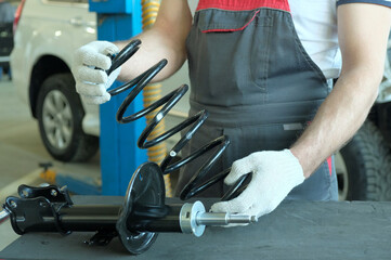 Spare parts for the car.Shock absorber strut and spring.A car service specialist checks the...