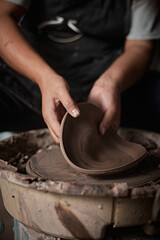 Hands of craftsman artist working on pottery wheel.