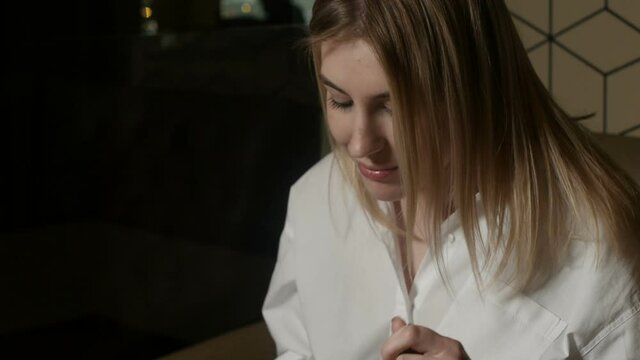 shooting near a blonde girl eating a dish sitting in a restaurant against a beige wall. High quality FullHD footage