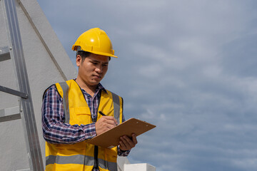 An architect engineer in a work uniform with a construction helmet and holding a pam, papers and pens.