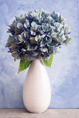 Bouquet of hydrangea flowers in a simple white vase;  Bouquet of hydrangea flowers and vase against...