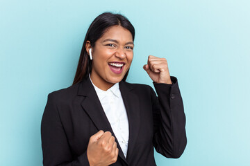 Young Venezuelan business woman isolated on blue background raising fist after a victory, winner concept.