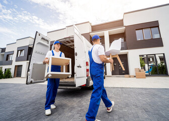 Two removal company workers unloading boxes and furniture from minibus