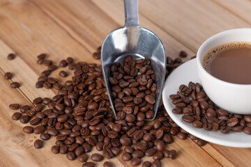  Coffee cup with a spoon scooping up coffee beans on table.