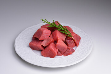 Pile of beef cubes on plate. Fresh raw diced red beef meat. Fresh raw beef cutting in small pieces.  Concept for sale in supermarket for client. 