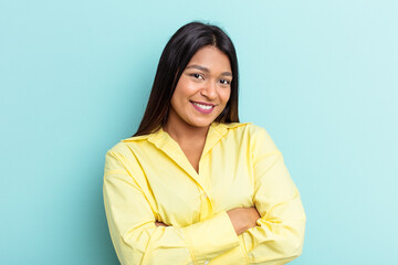 Young Venezuelan woman isolated on blue background who feels confident, crossing arms with determination.