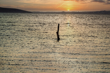 Fototapeta na wymiar a stake in the ocean at sunset