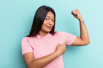 Young Venezuelan woman isolated on blue background showing strength gesture with arms, symbol of feminine power