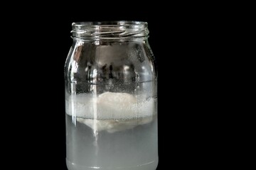 white flour powder dissolving in a glass of water on black background