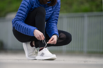 Female jogger tying her shoelaces in a park