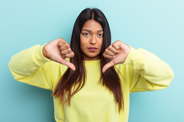 Young Venezuelan woman isolated on blue background showing a dislike gesture, thumbs down. Disagreement concept.