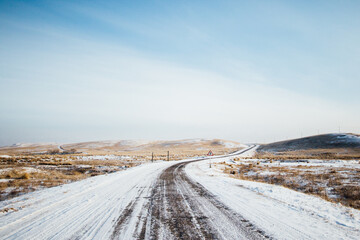 Snowy winter road in Khakassia with fields and mountains in the background