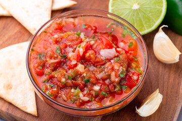 Salsa Asada sauce with roasted vegetables, served with tortilla chips and lime, closeup