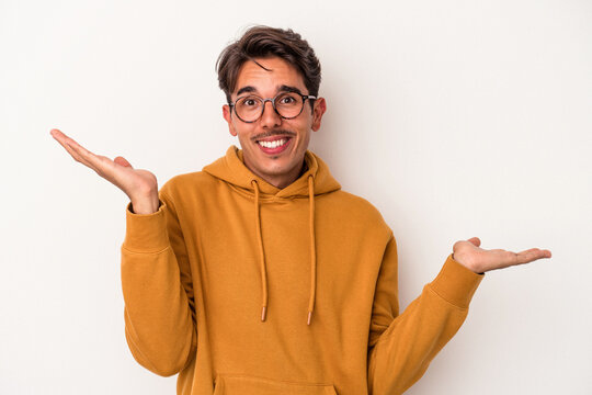 Young mixed race man isolated on white background confused and doubtful shrugging shoulders to hold a copy space.