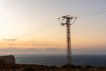 Power lines in a mountainous landscape at sunset.