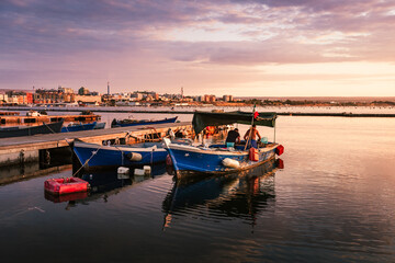 Fototapeta premium Port of the village of Taranto Vecchia at dawn with fishermen working on the boat