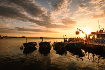 Boats moored in the port of Taranto Vecchia with the rising sun behind them