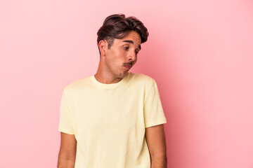 Young mixed race man isolated on white background shrugs shoulders and open eyes confused.