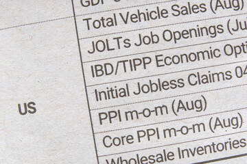 A table listing expected release of various government reports on the US economy. A newspaper listing upcoming US economic reports for business and investment community. Macro closeup view.