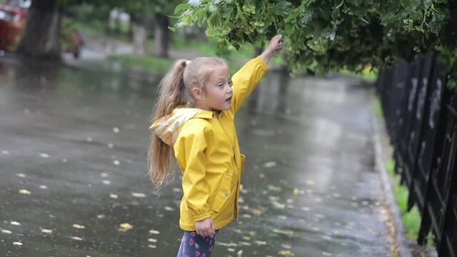 A child in a yellow raincoat is having fun in a city park