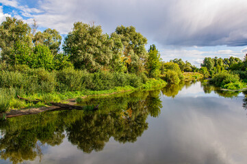 Beautiful landscape with the Teterev river in the foreground and the reflection of trees in the water