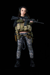 Fototapeta premium Young woman stands with a rifle on a black background