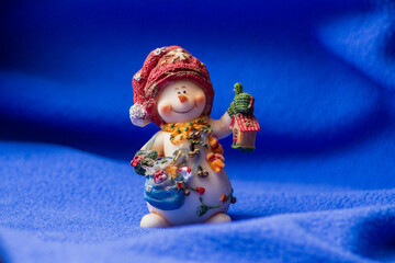 A toy snowman with a lantern is waiting for Christmas and New Year