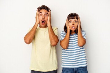 Young mixed race couple isolated on white background being shocked, she has remembered important meeting.