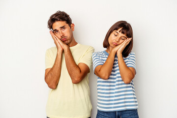 Young mixed race couple isolated on white background yawning showing a tired gesture covering mouth with hand.