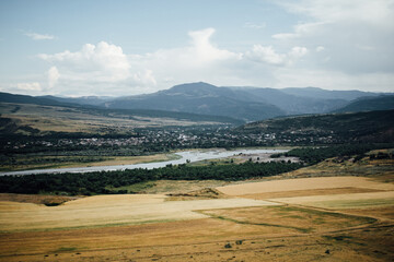Beautiful natural landscape in Georgia with a view of the mountain, city, flowing river and field