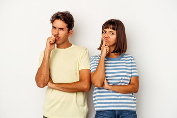Young mixed race couple isolated on white background unhappy looking in camera with sarcastic expression.