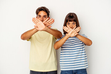 Young mixed race couple isolated on white background doing a denial gesture