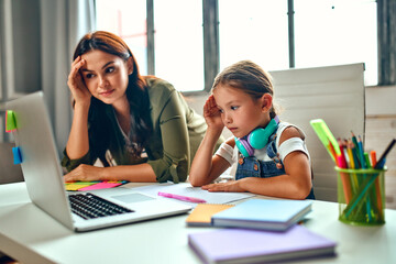 Online training. Very difficult lessons. Schoolgirl with her mother listen to a lesson on a laptop. School at home in a pandemic and quarantine.