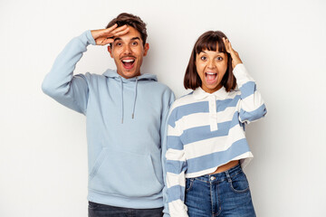 Young mixed race couple isolated on white background shouts loud, keeps eyes opened and hands tense.