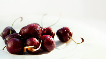juicy ripe cherries lie on a white table in the glare of light. copy space