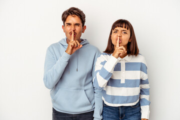 Young mixed race couple isolated on white background keeping a secret or asking for silence.