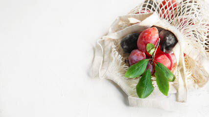 Fresh plums in a reusable mesh shopping bag. Flat surface, autumn background. Ripe organic plums in an eco-bag. Soft focus. concept of zero waste. copy space . banner