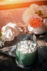 Obraz na płótnie Canvas coffee with marshmallows. a delicious drink made of cocoa or hot chocolate with marshmallows in a cup on a wooden table. Still life in a rustic style with a beautiful openwork light