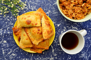 on a blue background a plate with fresh pastries and a cup of aromatic coffee or tea for breakfast