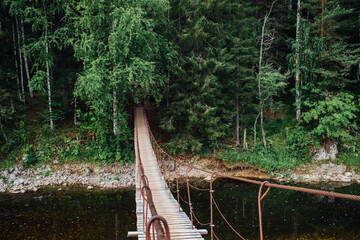 A beautiful suspension bridge over the river flowing in the Olenyi Streams park in the Sverdlovsk region