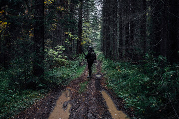 A hunter stands with a gun on a forest road in the Russian forest