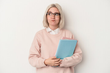 Young caucasian student woman holding books isolated on white background confused, feels doubtful...