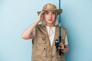 Young caucasian fisherwoman holding a rod isolated on blue background being shocked, she has remembered important meeting.