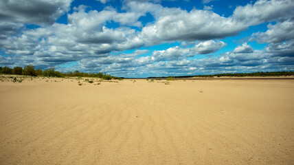 sandy coast against the backdrop of cumulus clouds on a sunny day, landscape