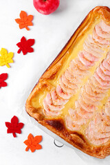 Apple pie with custard cream on the puff pastry on the white table. Autumn homemade dessert