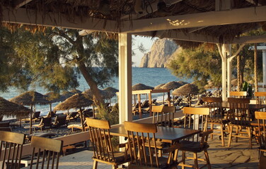 View of empty restaurant tables in the early morning at Kamari Beach, Santorin, Greece