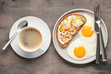 Sandwich with cheese, cucumber and shrimp, fried eggs on a plate and coffee on the table. Healthy breakfast. Top View