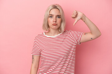 Young caucasian woman isolated on pink background showing a dislike gesture, thumbs down....