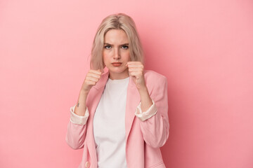 Young caucasian woman isolated on pink background throwing a punch, anger, fighting due to an argument, boxing.