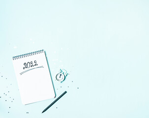 Top view of white vintage alarm clock and empty notebook ready for New 2022 Year planing or wish...